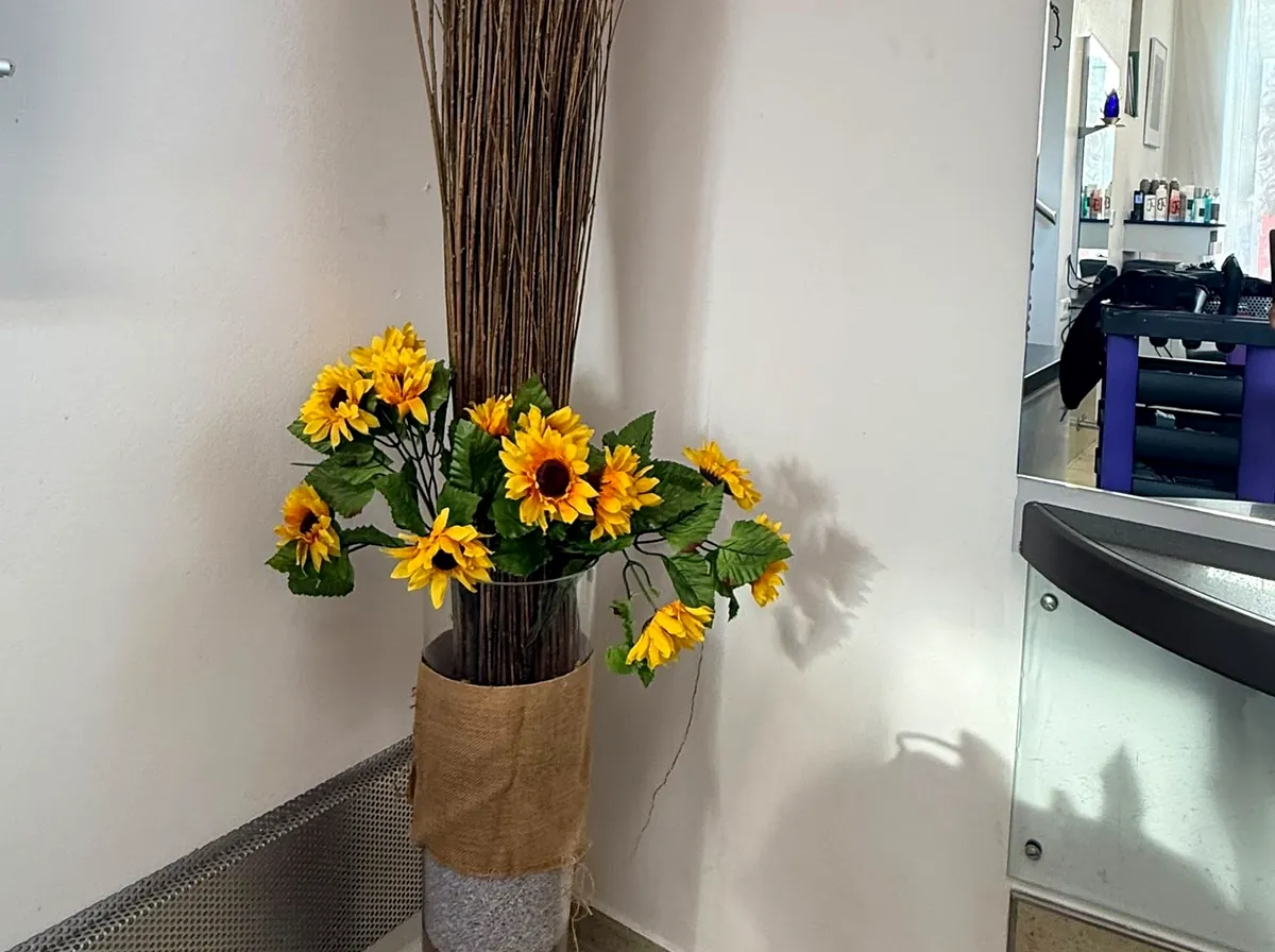 Sonnenblumen und Zweige in einer hohen Glasvase, Dekoration im Salon.
